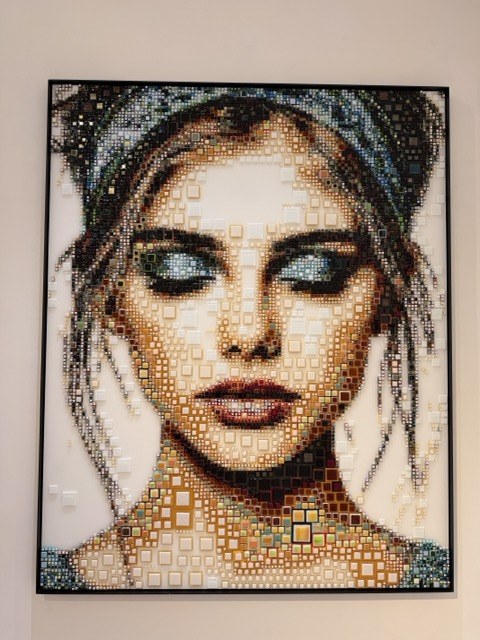 Mosaic-style portrait of a woman's face on a gallery wall at Nit de l'Art