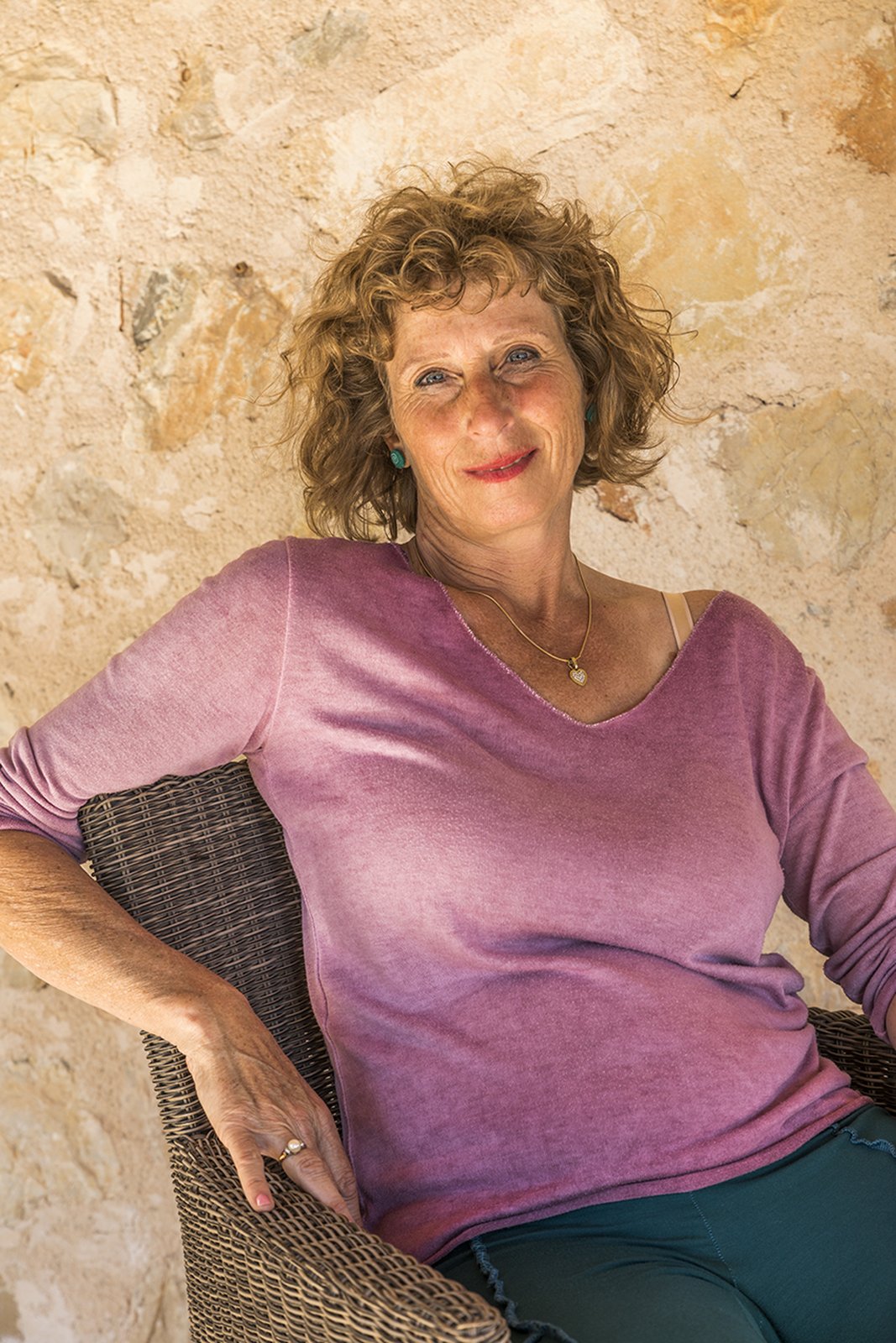 Energetic coach Silke Maria Haas relaxing against a stone wall in Mallorca