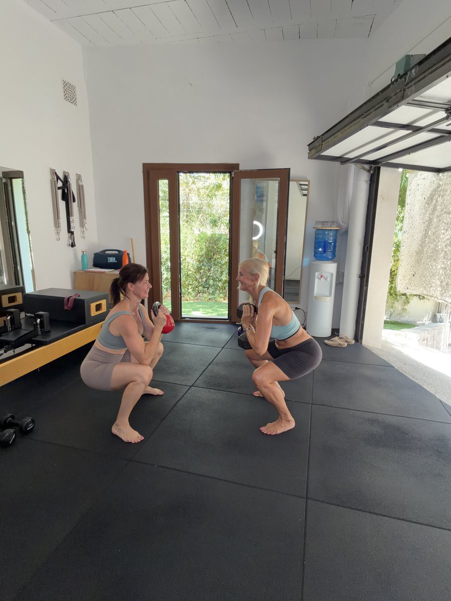 Amanda J Butler and trainer Kate Sotelo performing a deep squat together in a Mallorca training studio