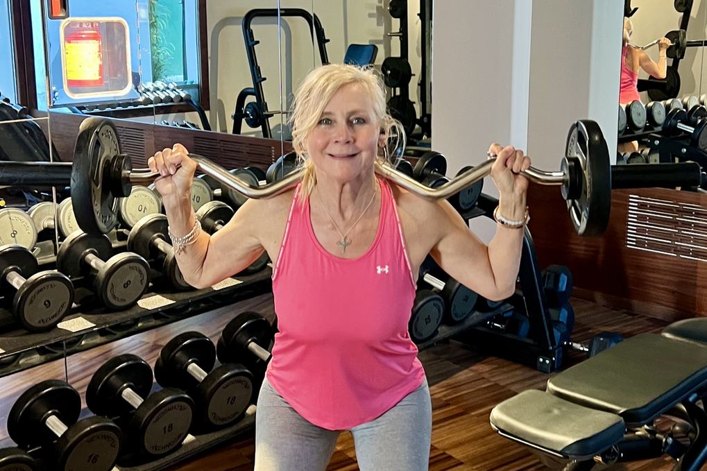 Amanda J Butler lifting a barbell in the gym as part of her strength training for bone health