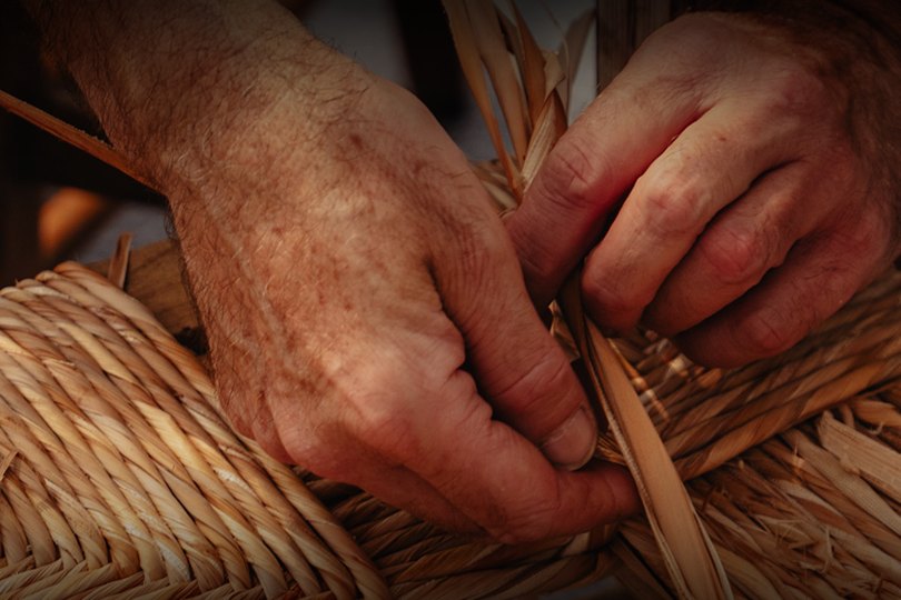 Artisan hands weaving a traditional rush chair seat at the BaleArt craft fair, Palma