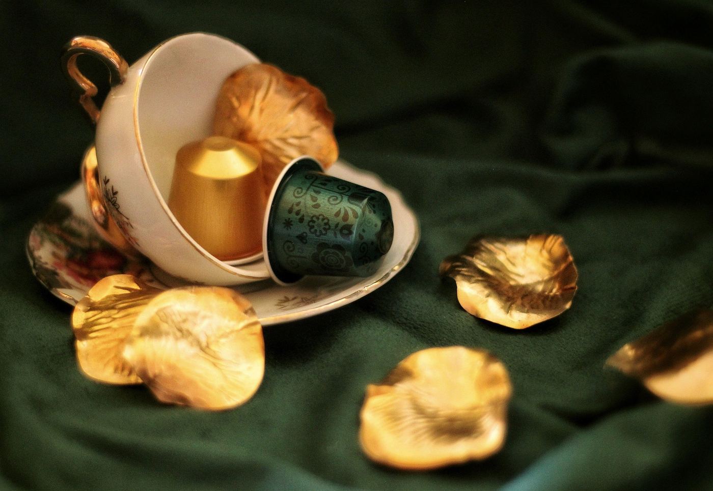 Two aluminium coffee capsules resting in a vintage china teacup
