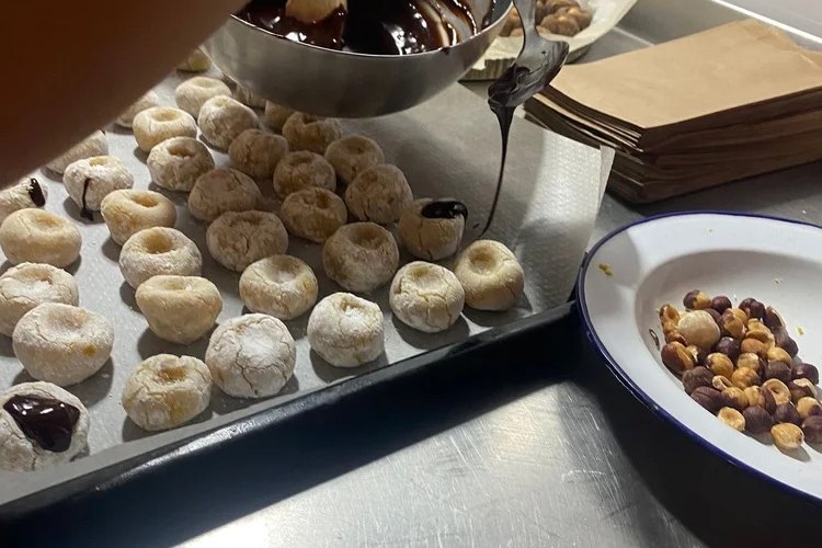 Chocolate being drizzled over freshly baked panellets at Forn de sa Llotgeta, Palma, for All Saints