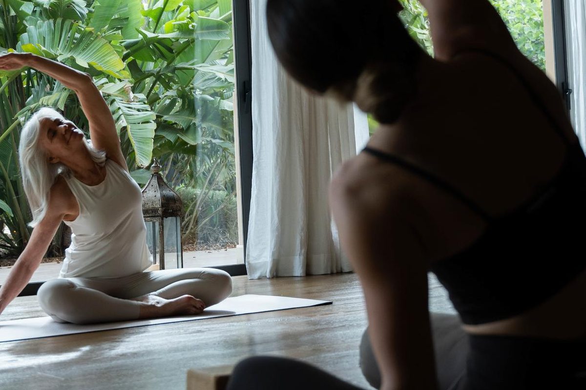 Women stretching on yoga mats in a garden-view yoga room at Cal Reiet, Purity and Clarity yoga retreat, Mallorca