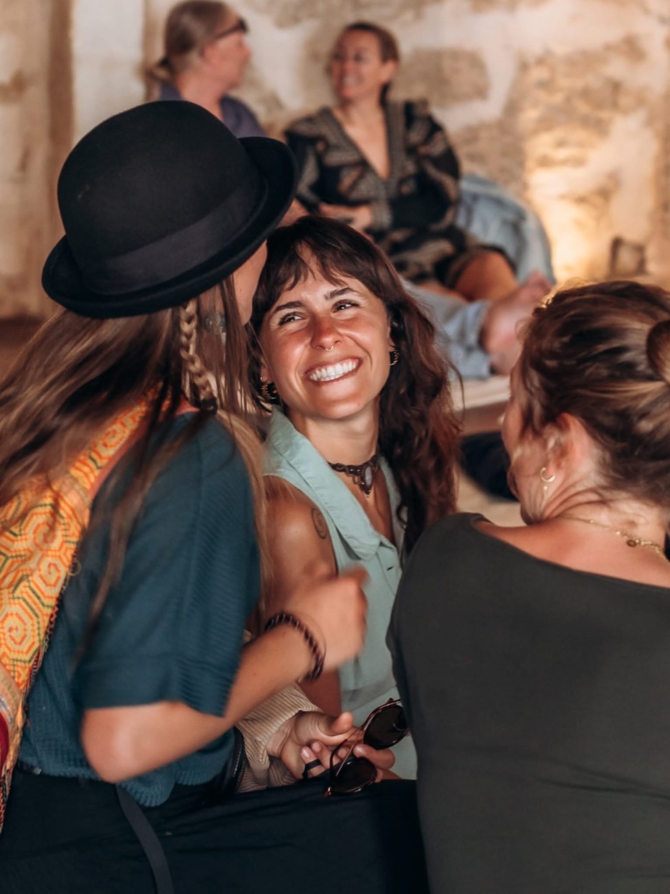 Women laughing and embracing at a wellbeing gathering at Sadhana Works, Mallorca